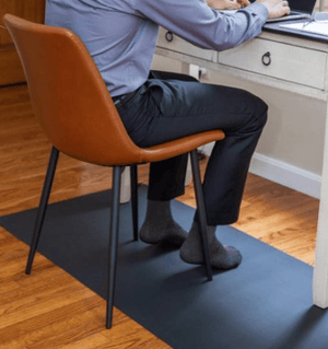 Man wearing socks at desk on floor mat